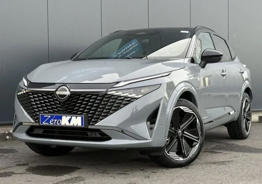 Nissan Qashqai 2025 gris Ceramic en 3/4 avant droit avec toit panoramique et jantes alliage noires.