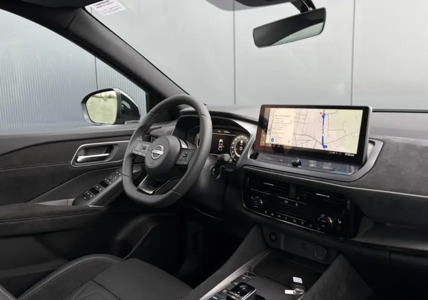 Vue intérieure côté conducteur du Nissan Qashqai 2025 gris Ceramic, avec volant cuir, écran tactile GPS et sellerie Alcantara.