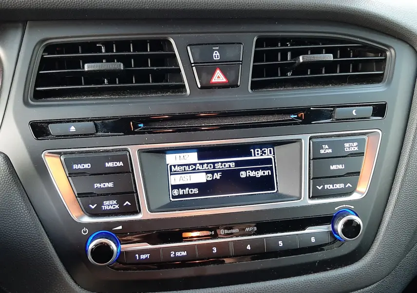 Vue rapprochée du tableau de bord de la Hyundai i20 blanche 2016, mettant en valeur l’écran multimédia et les commandes centrales.