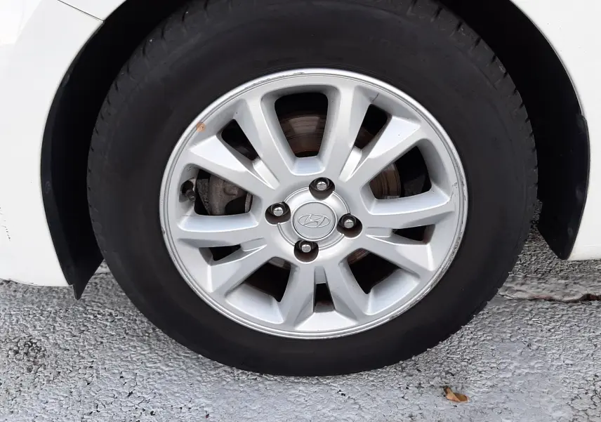 Gros plan sur la roue avant gauche d'une Hyundai i20 blanche de 2016 avec jante alliage argentée et logo Hyundai au centre.