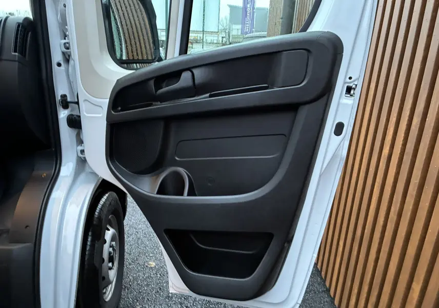 Vue rapprochée de la porte avant gauche ouverte du Fiat Ducato Fourgon blanc 2025, mettant en valeur le panneau intérieur noir.