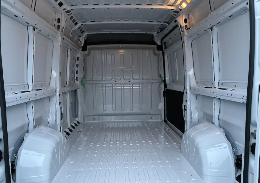 Vue intérieure arrière du fourgon blanc FIAT Ducato 2.2 140 L2H2 2025, montrant l'espace de chargement vide et les parois métalliques.