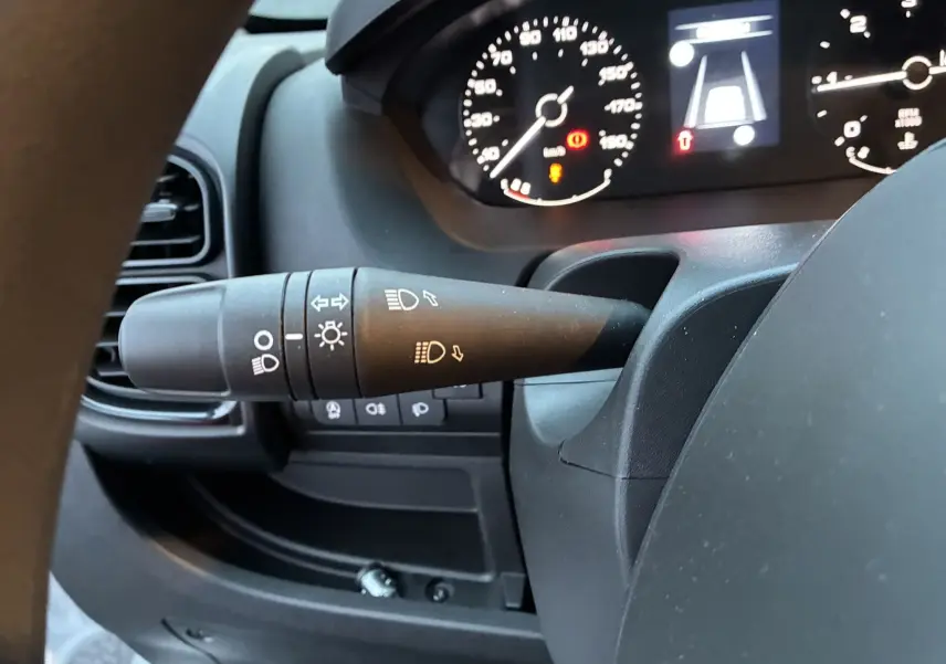 Gros plan sur la manette de commandes d’éclairage à gauche du volant dans l’habitacle noir du Fiat Ducato Fourgon blanc 2025.