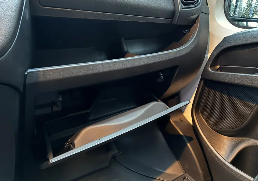 Vue intérieure côté passager du Fiat Ducato Fourgon 2025, boîte à gants ouverte avec tableau de bord noir et détails en tissu.
