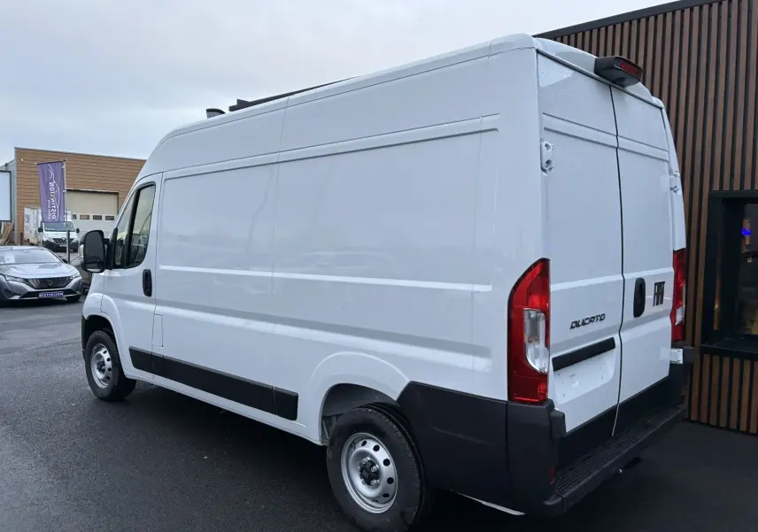 Vue 3/4 arrière droite d’un FIAT Ducato Fourgon blanc 2025 avec portes arrière battantes et protections noires.