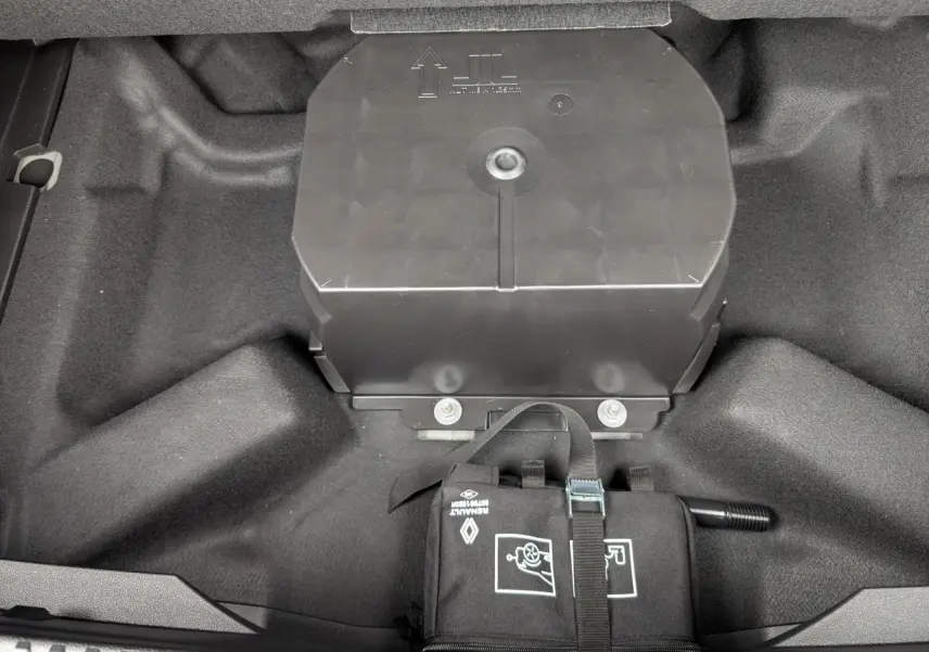 Vue plongeante sur le coffre gris du Renault Austral 2025, montrant le rangement sous plancher avec kit de réparation pneus.