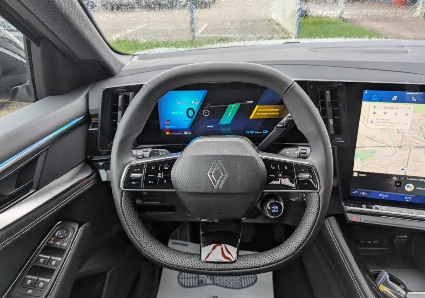Vue intérieure centrée sur le volant et tableau de bord numérique du Renault Austral gris avec écran tactile latéral.
