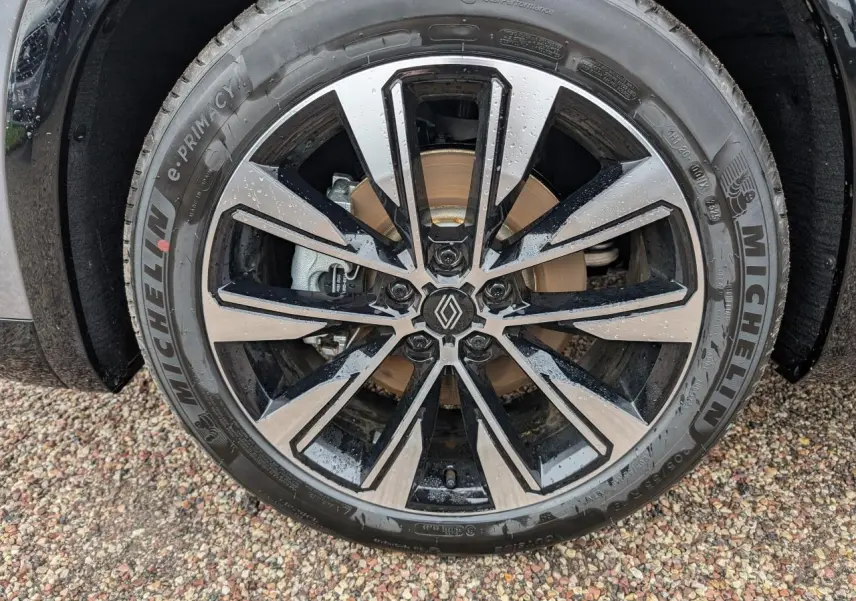 Gros plan sur la jante alliage diamantée noir brillant du Renault Austral gris, avec logo central visible.