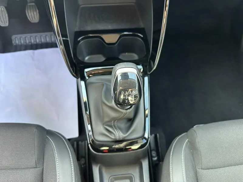 Vue intérieure centrée sur le levier de vitesses manuel noir, entouré des sièges tissu noir de la Citroën C3 2025.