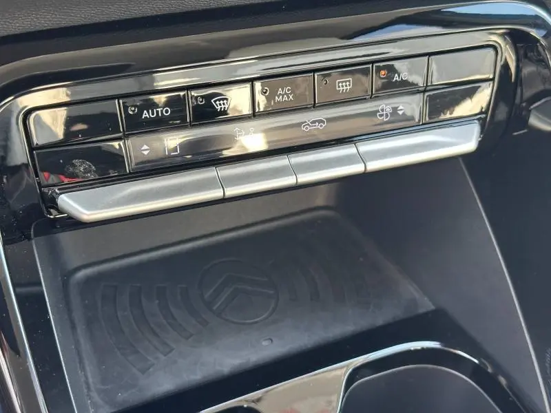 Vue rapprochée de la commande de climatisation automatique et du chargeur sans fil noir dans une Citroën C3 2025 Bright Blue.