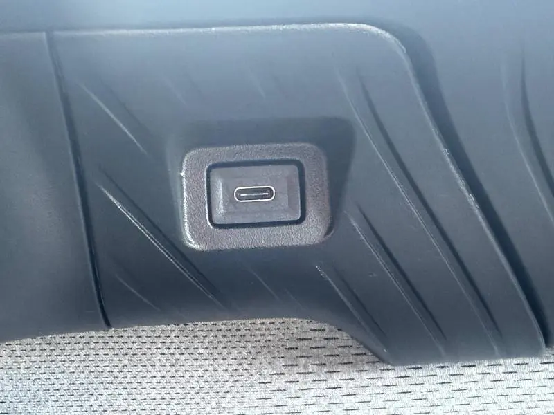 Gros plan sur une prise USB-C intégrée dans le revêtement intérieur noir et tissu clair d'une Citroën C3 2025 Bright Blue.