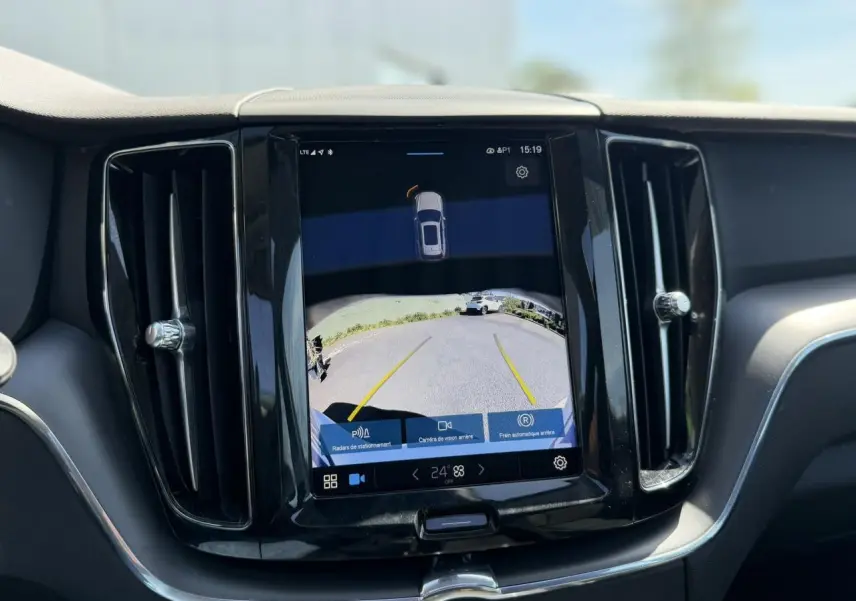 Écran tactile central du tableau de bord du Volvo XC60 blanc, affichant la caméra de recul avec lignes de guidage jaunes.