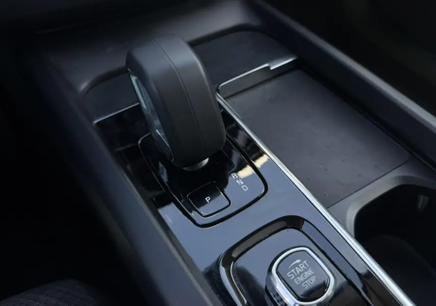 Gros plan sur la console centrale noire du Volvo XC60 2024 avec levier de vitesse automatique et bouton Start/Stop.