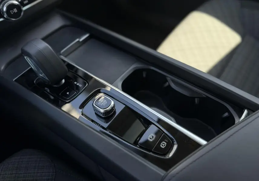 Gros plan sur la console centrale noire du Volvo XC60 blanc, avec levier de vitesse et bouton Start/Stop.