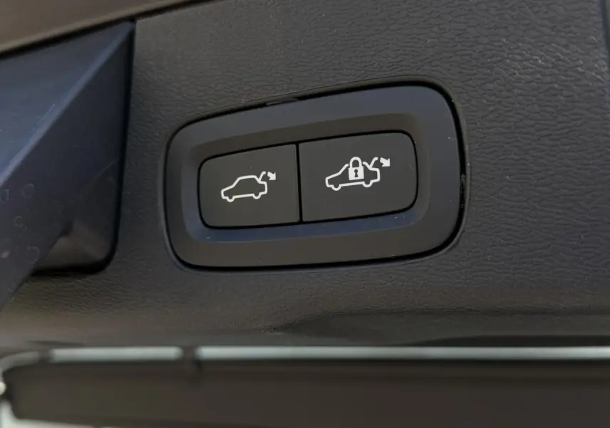 Gros plan sur les boutons de commande du hayon électrique du Volvo XC60 blanc Crystal, intérieur noir.