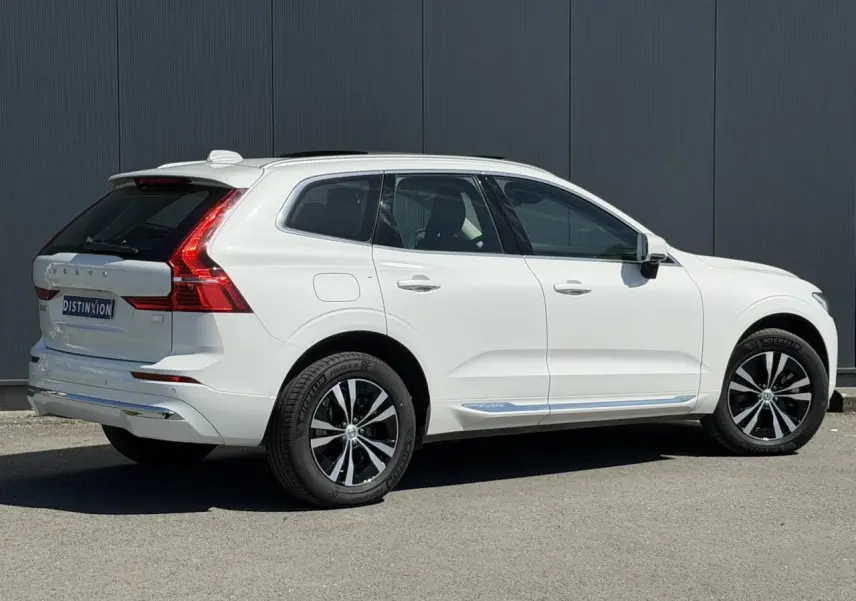 Vue 3/4 arrière droite du Volvo XC60 blanc Crystal avec jantes alliage noires et chrome autour des vitres.