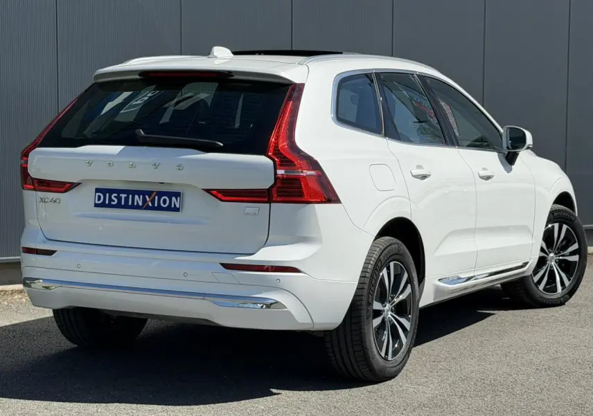 Vue 3/4 arrière droite du Volvo XC60 blanc Crystal avec jantes alliage et contours chromés des vitres.
