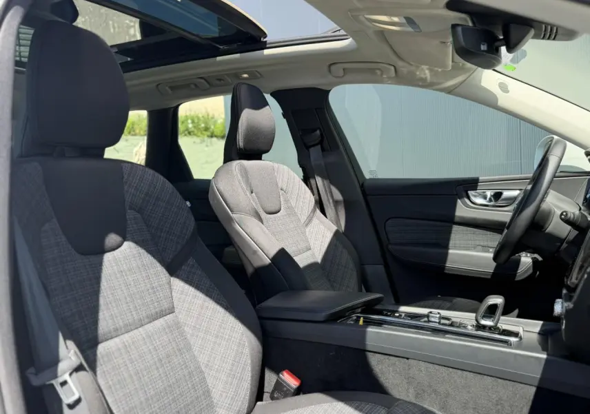 Vue intérieure côté droit du Volvo XC60 2024 T6 AWD PHEV, sièges tissu gris et toit ouvrant panoramique visible.