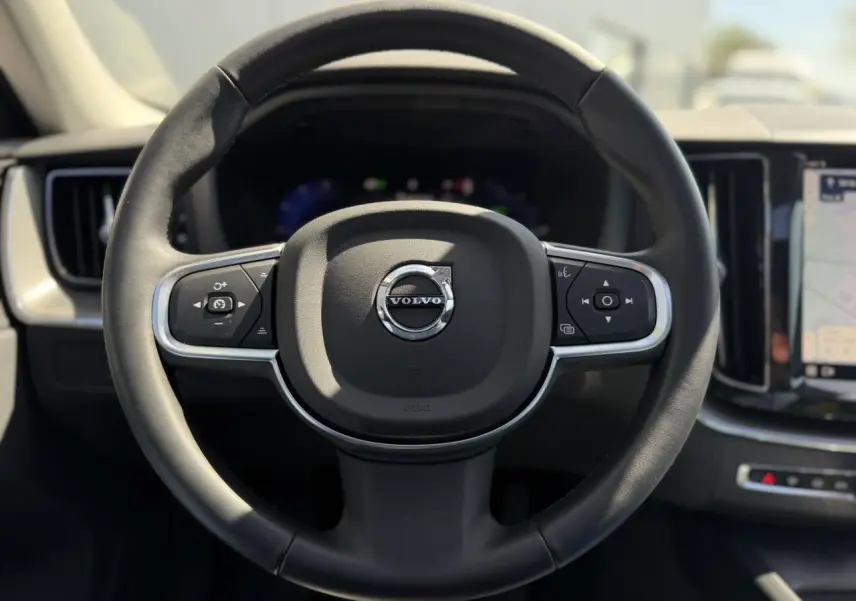 Volant 3 branches en simili-cuir noir de Volvo XC60 T6 AWD PHEV 2024, avec tableau de bord digital et écran tactile visible.
