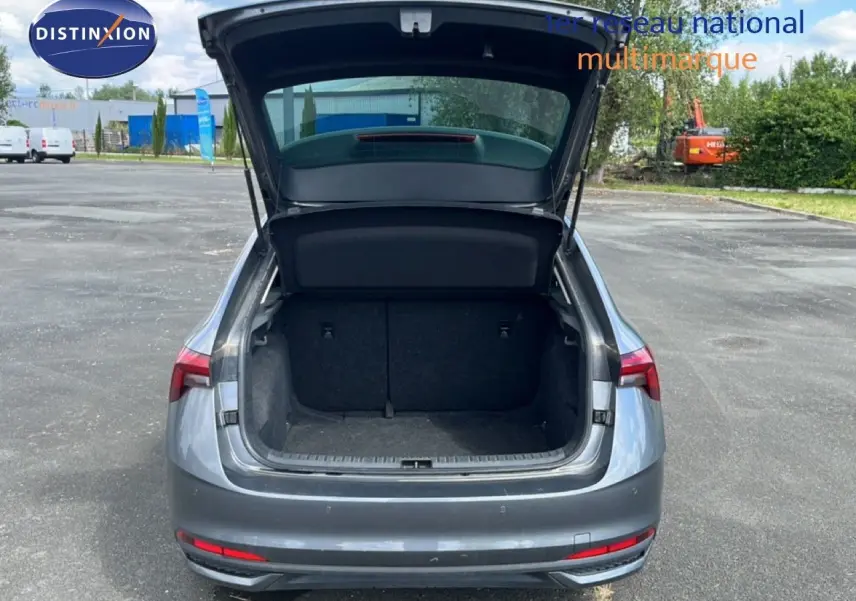 Vue arrière d’une Skoda Scala gris magnétique métal 2025 avec coffre ouvert sur un parking extérieur.