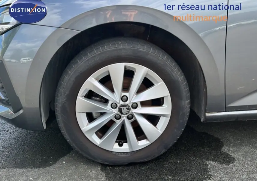 Gros plan sur la roue avant gauche d’une Skoda Scala gris magnétique métal avec jante alliage 16 pouces.