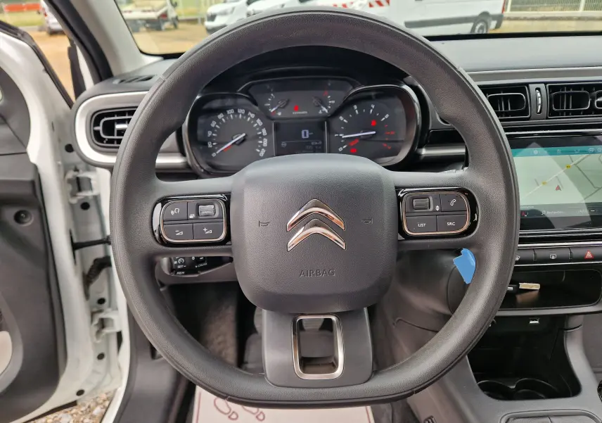 Vue intérieure centrée sur le volant noir de la Citroën C3 Société blanche, avec tableau de bord et écran tactile visibles.