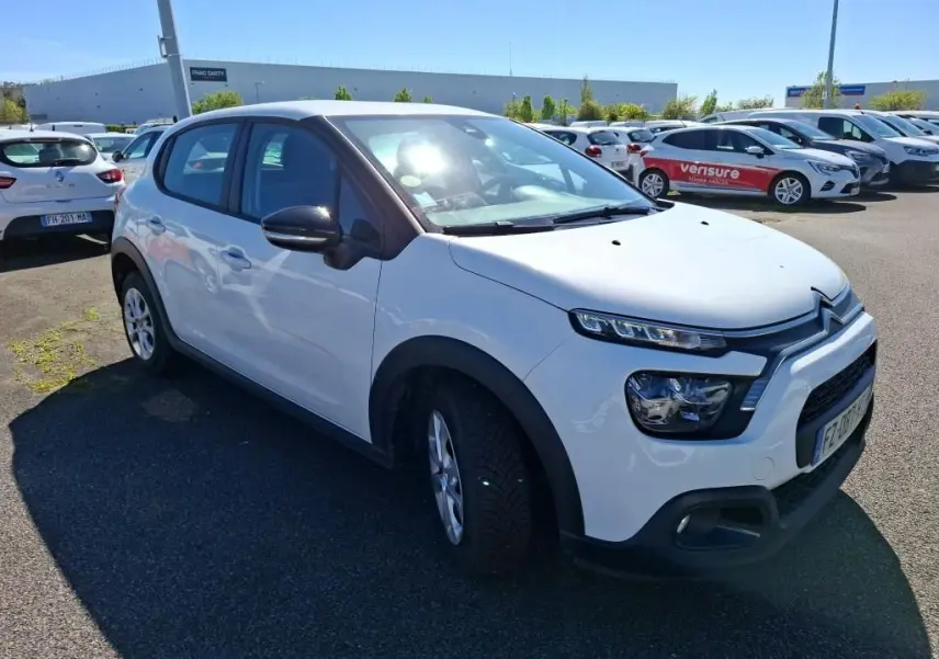 Citroën C3 Société blanc vue 3/4 avant droit, avec phares distinctifs et protections noires sur les ailes.