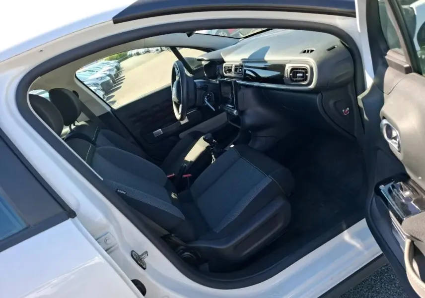 Intérieur avant droit de la Citroën C3 Société blanche 2021, montrant les sièges tissu et tableau de bord noir brillant.