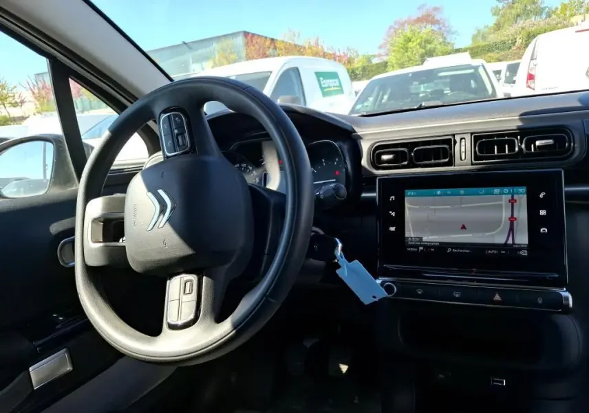 Vue intérieure côté conducteur de la Citroën C3 Société blanche, avec volant multifonction et écran tactile affichant la navigation.