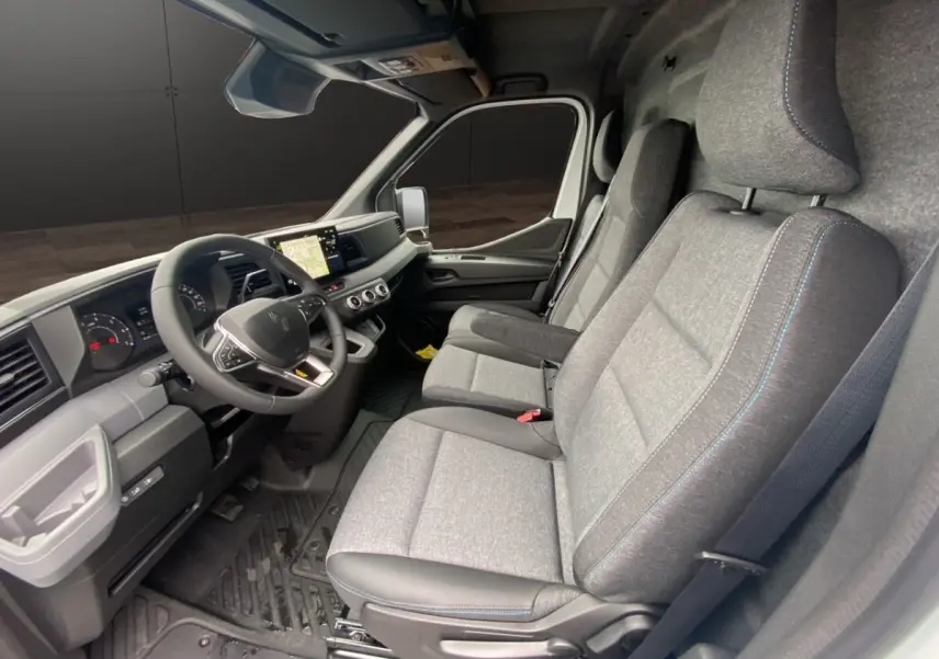 Vue intérieure côté conducteur du Renault Master 2026, sièges gris avec surpiqûres bleues et tableau de bord moderne.
