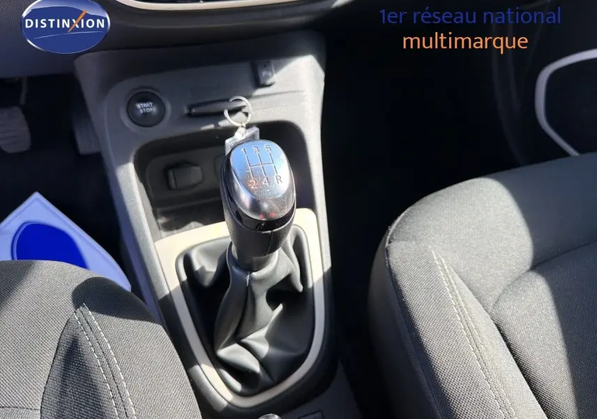 Gros plan sur la console centrale du Renault Captur gris cassiopée, mettant en valeur le levier de vitesse manuel et les sièges tissu noir.