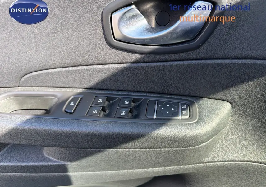 Gros plan sur la porte côté gauche du Renault Captur gris Cassiopée, montrant les commandes des vitres et la poignée intérieure.