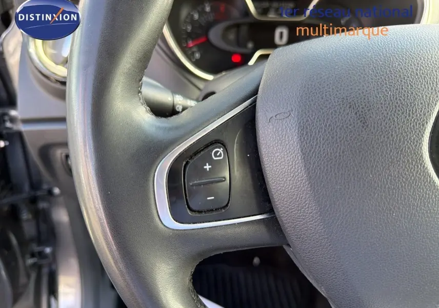 Gros plan sur le volant noir du Renault Captur gris Cassiopée, montrant les commandes de régulateur de vitesse à gauche.
