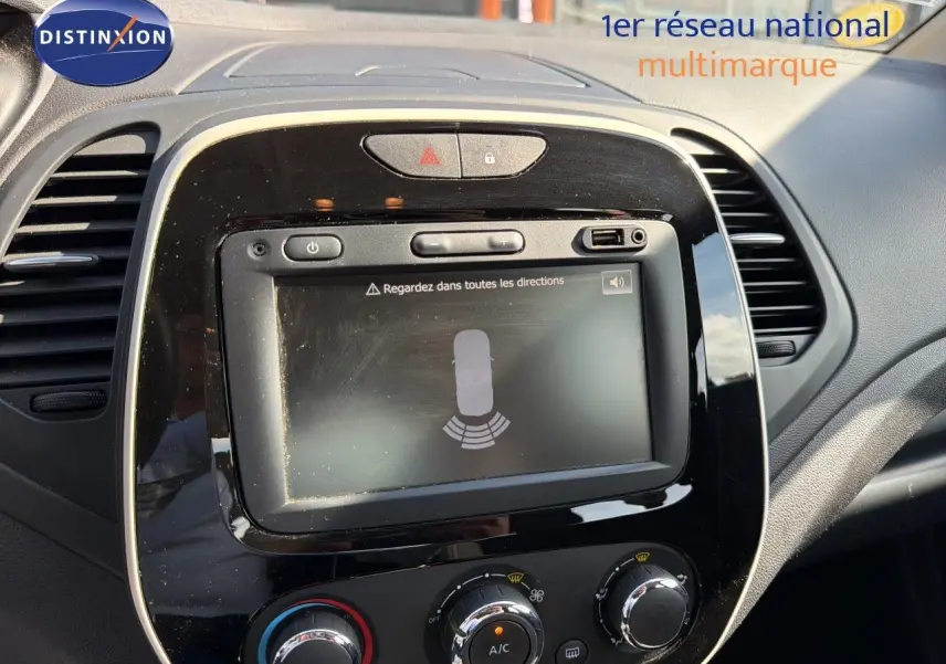 Vue rapprochée de l’écran tactile et de la console centrale noire du Renault Captur gris Cassiopée, avec commandes de climatisation visibles.
