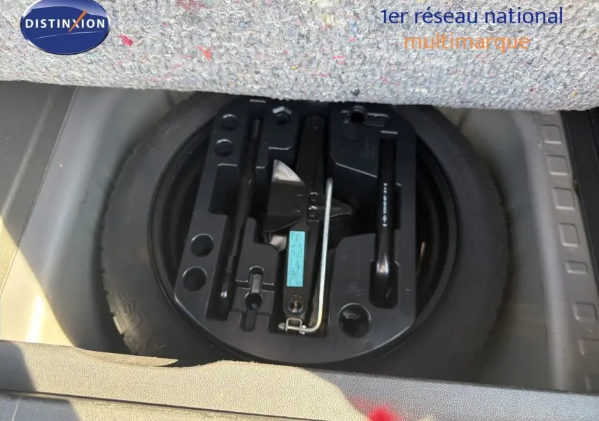 Gros plan sur la roue de secours et le kit de réparation sous le tapis du coffre du Renault Captur gris Cassiopée.