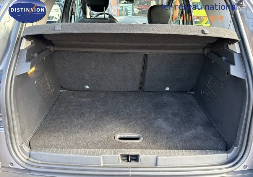 Coffre ouvert vu de l'arrière d'un Renault Captur gris Cassiopée, montrant l'espace de chargement vide et la tablette cache-bagages.