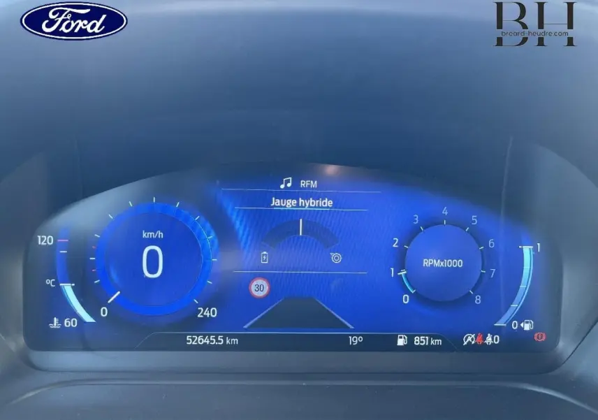 Tableau de bord numérique du Ford Puma 2024, affichage bleu avec jauge hybride et compte-tours à 0 RPM.