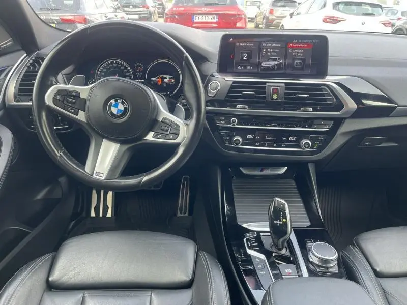 Vue intérieure du poste de conduite du BMW X3 M40iA 2019 avec volant cuir noir et écran tactile central.