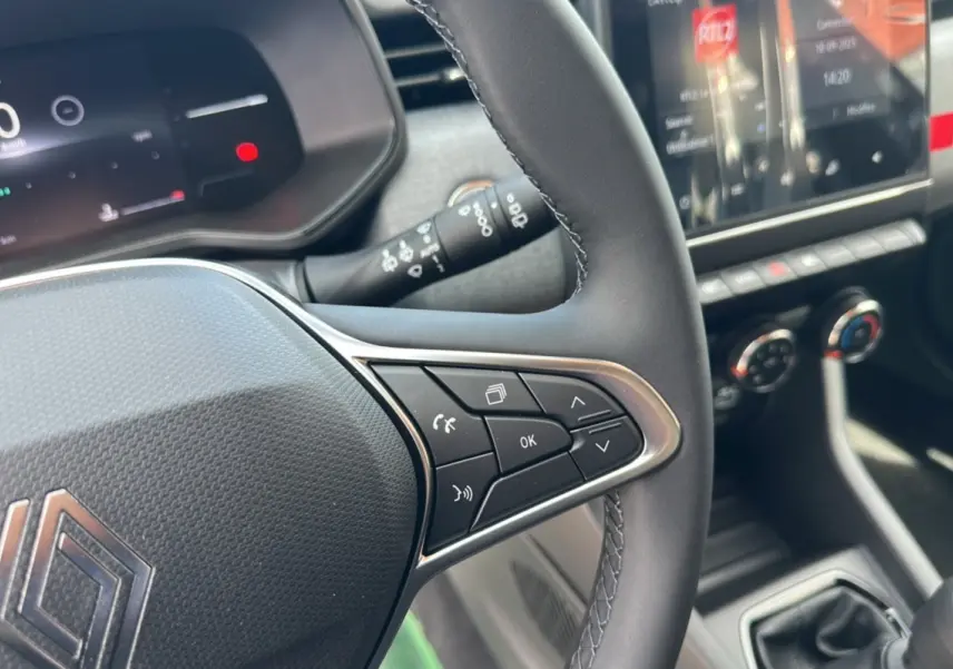 Vue rapprochée du volant de la Renault Clio DCI 100 Evolution Camera 2025 avec commandes intégrées et tableau de bord numérique.