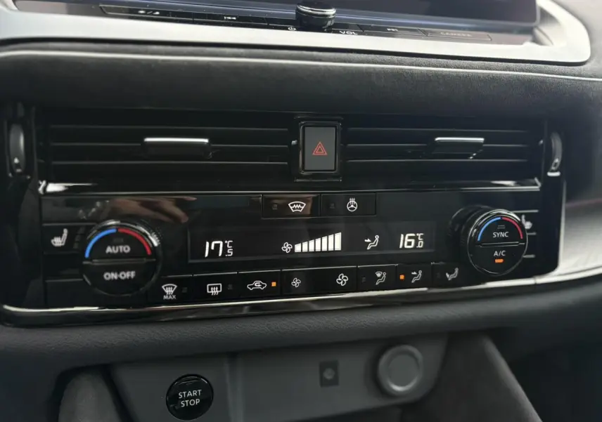 Tableau de bord du Nissan Qashqai 2025 avec commandes climatisation bi-zone et bouton start/stop en vue rapprochée.