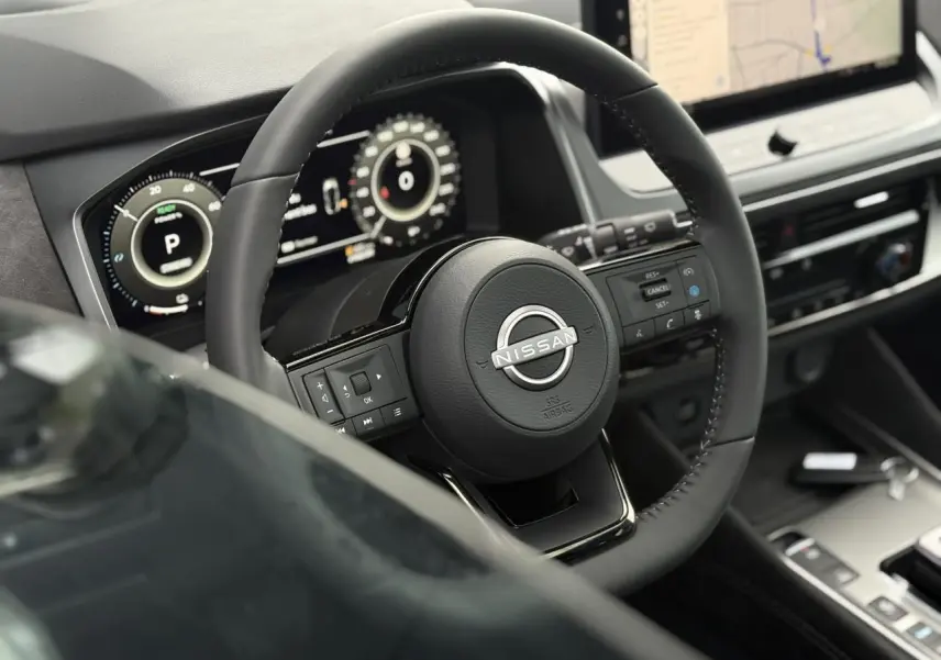 Vue rapprochée du volant cuir Nissan Qashqai 2025 avec commandes intégrées et tableau de bord numérique.