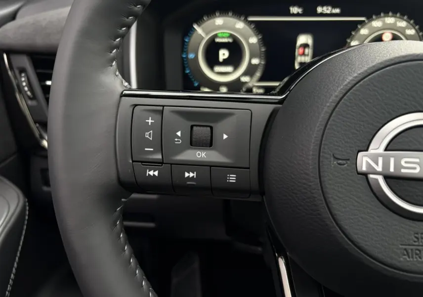 Gros plan sur le volant cuir noir côté gauche du Nissan Qashqai 2025 avec commandes intégrées et tableau de bord numérique.