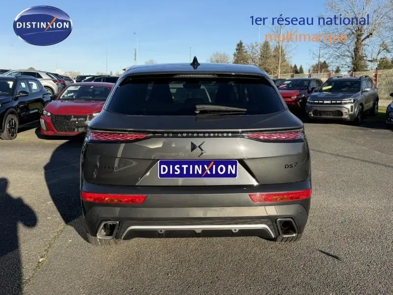 Vue arrière d'un DS7 E-TENSE 225ch Performance Line gris titane, soulignant ses feux LED et double sortie d'échappement intégrée.