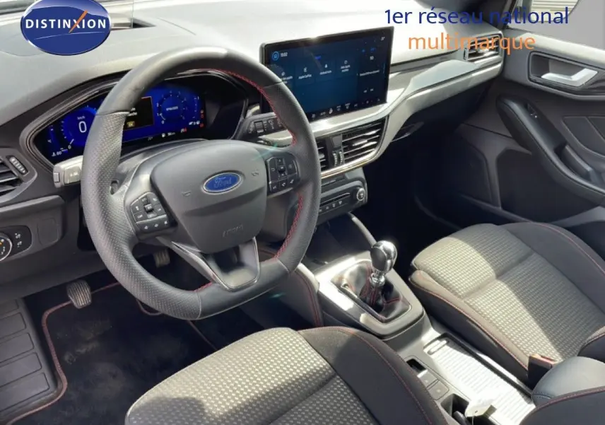 Vue intérieure avant droite de la Ford Focus SW 2023, volant cuir noir, tableau de bord numérique et console centrale avec boîte manuelle.