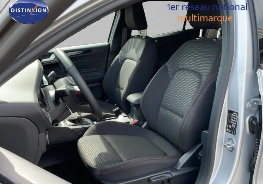 Vue intérieure côté conducteur de la Ford Focus SW gris lunaire, sièges tissu noir avec surpiqûres rouges et volant cuir.