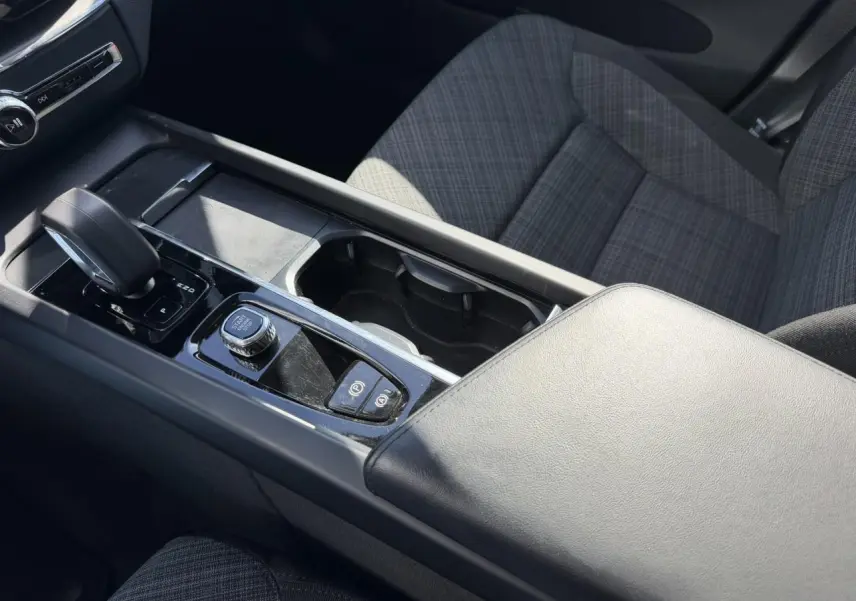 Vue intérieure rapprochée de la console centrale et accoudoir en simili-cuir gris du Volvo XC60 T6 AWD PHEV 2024.