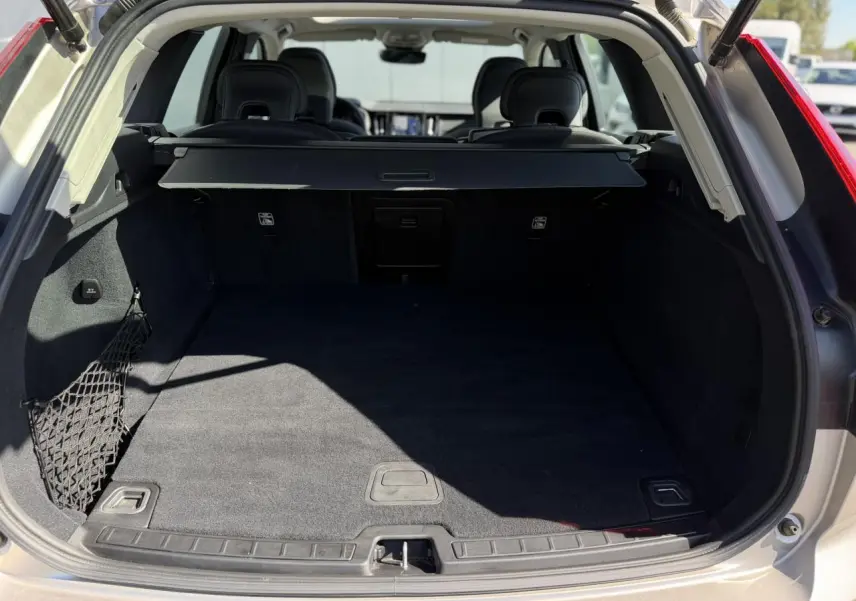Coffre ouvert d’un Volvo XC60 gris Dusk 2024, vue arrière montrant l’espace de chargement et la plage arrière.