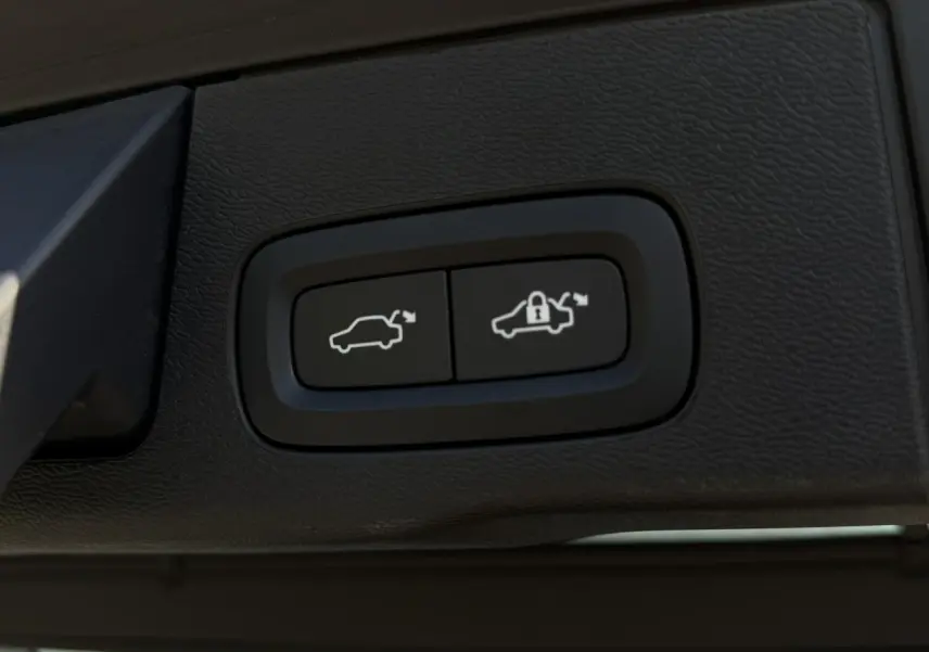 Gros plan sur les boutons d'ouverture et de verrouillage du hayon électrique du Volvo XC60 gris Dusk.