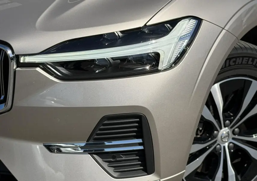 Gros plan sur l'avant droit du Volvo XC60 gris Dusk, mettant en valeur le phare LED et la jante alliage 18 pouces.