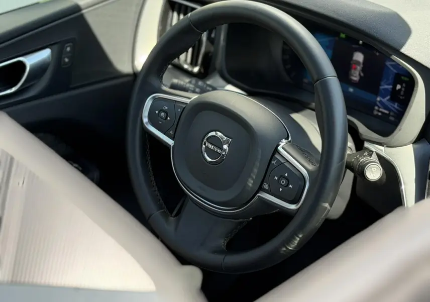 Vue rapprochée du volant noir et du tableau de bord digital du Volvo XC60 T6 AWD PHEV 2024, intérieur gris.